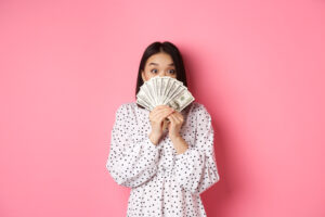 shopping concept cute asian woman hiding face behind money dollars peeking at camera standing over p